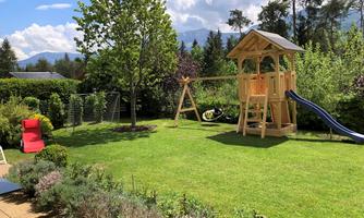 A beautiful garden with a slide and a playground. The sun is shining and the sky is clear.