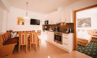 A modern kitchen with a dining area and wooden chairs. Bright walls and a pleasant atmosphere create coziness.