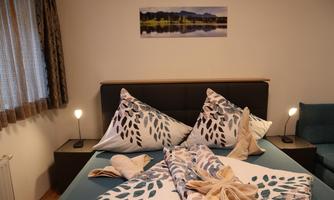 A cozy bedroom with a double bed and decorative pillows. A picture of a picturesque landscape hangs on the wall.
