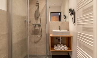 A modern bathroom with a glass shower and a stylish wooden sink. Clean towels are neatly arranged.