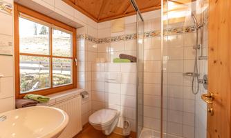 A modern bathroom with a shower and a sink. Large windows provide plenty of daylight and a bright atmosphere.