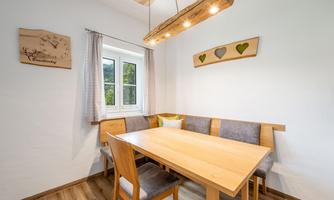 An inviting dining area with a wooden table and comfortable benches. The window offers a view of the outdoors and creates a bright atmosphere.