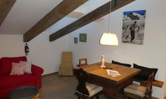 A cozy living space with wooden beams and modern furniture. A red sofa and a wooden table create an inviting atmosphere.