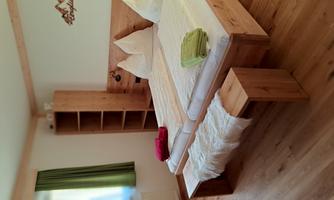 A cozy bedroom with a large bed. The furnishings are made of wood and there are colorful towels on the bed.