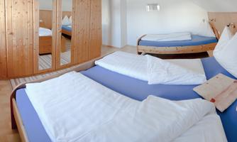 A cozy room with two beds and a modern wooden design. The space is bright and friendly with large mirrors.