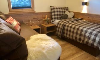 A cozy bedroom with wood decor and a single bed. The furnishings are in neutral colors, creating a pleasant atmosphere.