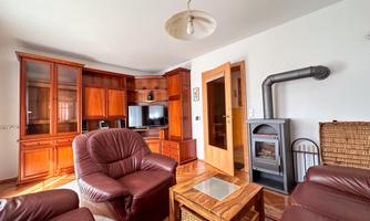 A cozy living room with brown leather furniture and a wood stove. Shelves with a TV and decor give the room an inviting atmosphere.