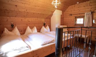 A cozy room with wooden walls and three beds. The decor is traditional and rustic, ideal for a relaxing stay.