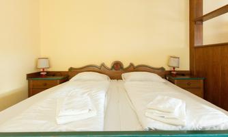 A cozy bedroom with two single beds and nightstands. The walls are painted in a soft yellow tone.