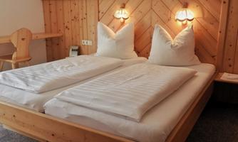 A cozy room with two single beds and wooden paneling. Soft lighting creates a relaxed atmosphere.