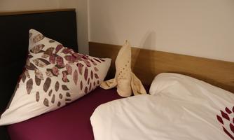 A cozy bed with a decorative pillow and an original cloth figure. The bedding is clean and harmoniously designed.