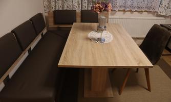 A modern dining area with a wooden tray and elegant chairs. A small floral decoration is positioned in the center of the table.
