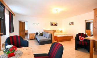 A cozy living space with a sofa, a dining area, and two armchairs. The room is bright and cheerfully designed.