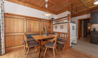 A cozy dining area with wood paneling and a wooden table. The surroundings are bright and inviting with a modern touch.