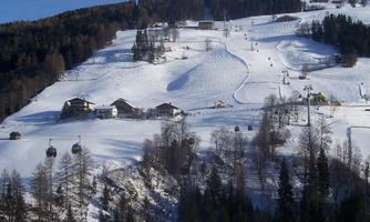 A Nevada landscape with cabins and ski lifts. The sky is clear and the mountains are full of freshly fallen snow.