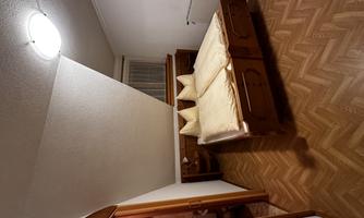 A cozy bedroom with a double bed and wooden furniture. The room has a wooden floor and is well lit.