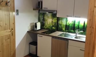 A modern kitchen with bright furniture and a green wall design. Basic kitchen appliances are available.