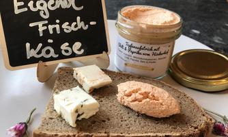 A piece of black bread with two types of cream cheese and a glass of cream cheese. Next to it is a sign that reads "Own Cream Cheese."