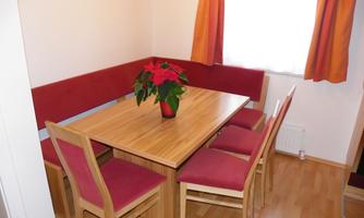 An inviting dining area with a wooden table and six chairs. On the table is a flower pot with a plant.