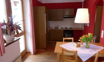 A cozy kitchen with red walls and wood details. The table is adorned with a white cloth and fresh tulips.