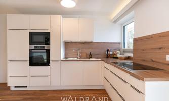 Modern kitchen with white cabinets and wooden surfaces. It features a built-in oven and a warm, inviting atmosphere.