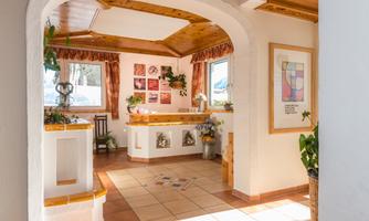 An inviting reception area with wooden elements and plants. Bright walls and windows let in plenty of light.