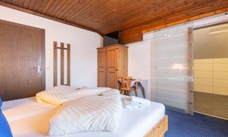 A cozy bedroom with a double bed and wooden paneling. The room is bright and invites relaxation.