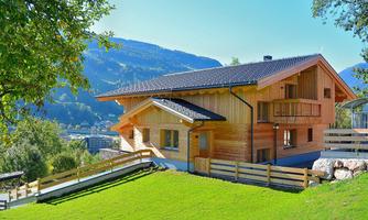 A modern wooden house in a picturesque landscape. The surroundings are green and mountainous, ideal for a quiet retreat.