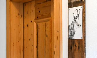 A wooden paneling with a door and a piece of artwork depicting the head of an animal is visible. The door is made of light wood and has a rustic appearance.