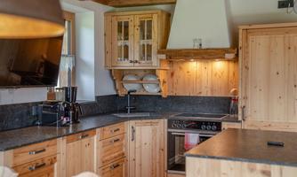 A cozy wooden kitchen with modern amenities. The walls are light and the surfaces are made of dark stone.