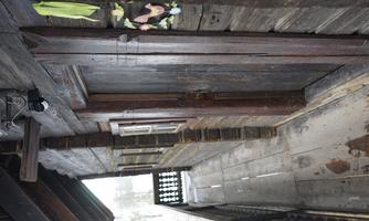 A traditional wooden house with a porch and a door made of dark wood. The walls are rustic, and some windows are visible.