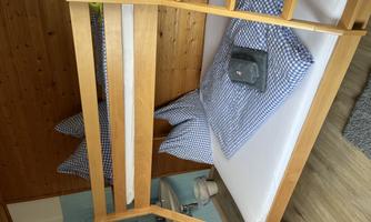 A simple room with a bunk bed. The bedding is blue checkered and the room has wood paneling.