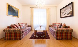 A cozy living space with two checked sofas and a table in the middle. Large windows provide plenty of daylight.