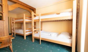 A room with two bunk beds and a green carpet. The walls are in a warm shade of yellow.