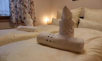 A cozy bedroom with two beds and lovingly folded towels. The soft light creates a relaxed atmosphere.
