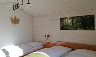 A bright bedroom with three beds and a cozy decor. On the wall hangs a picture of a forest landscape.