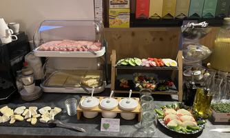 A buffet with cold cuts, cheese, and fresh vegetables. Fresh fruit and various sauces are also available.