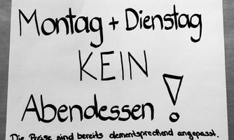A handwritten note on a white sheet of paper. It says: "Monday + Tuesday NO dinner!"