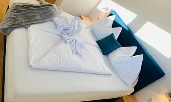 A cozy bed with white pillows and blankets. The room has a bright, inviting atmosphere.
