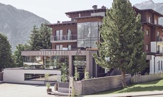 A modern building with large windows and a stylish design. Surrounded by trees and mountains, it offers an inviting atmosphere.