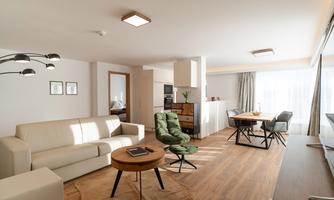 A modern living room with a bright couch and a round table. Generous windows let in plenty of daylight.