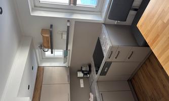 A modern kitchen with bright cabinets and a small dining area. The window lets in a lot of light and offers a view outside.