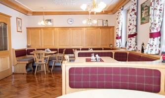A cozy dining area with wood paneling and red upholstered benches. The tables are simply and invitingly decorated.
