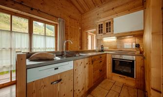 A cozy wooden kitchen with modern appliances and large windows. The room is bright and inviting.