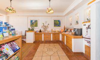 A reception area with wooden furniture and informational materials. The walls are decorated with pictures and there is a cozy atmosphere.