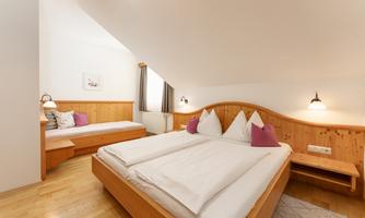 A bright bedroom with wooden details and two beds. The cozy decor creates an inviting atmosphere.