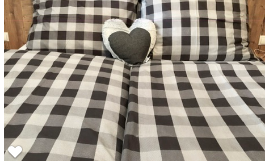 A bed with checkered bed covers in black and white. In the middle lies a heart-shaped pillow.