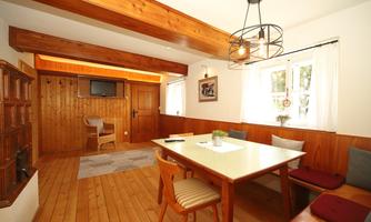 A bright dining room with a wooden ceiling and rustic furniture. A large table and some chairs provide space for sociability.