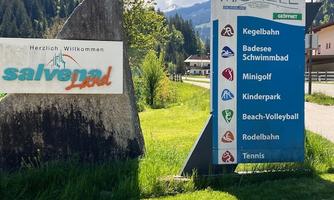 A welcome sign from Salvenaland with various leisure activities listed below. The sign showcases activities such as bowling, mini golf, and a children's park in a green environment.