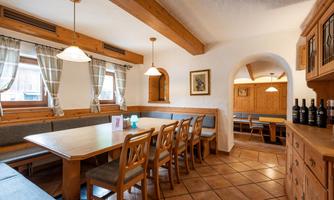 A cozy dining room with wood paneling and a long table. The atmosphere is inviting and rustic.